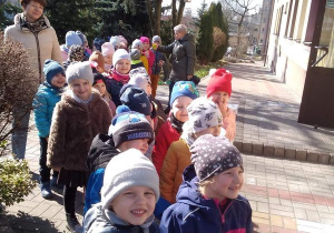 Dzieci stoją przed budynkiem przedszkola